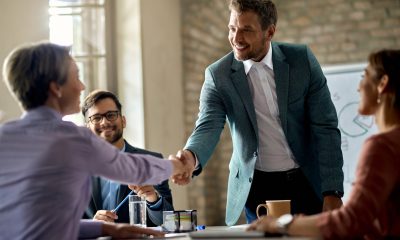 Happy businessman greeting a female colleague on a meeting in th Business coworkers shaking hands during a meeting in the office. Focus is on a businessman.